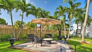 A patio area with a table and chairs, a fire pit, and a wooden fence. - 5 Bedroom Mini Resort with Pool! (Boynton Beach)