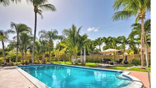 Piscina rodeada por palmeiras e uma cerca de madeira.