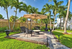 Een terras met buitenmeubilair, een pergola en een houten omheining.