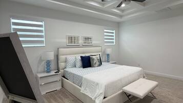 A bedroom with a bed, bedside tables, a ceiling fan, and a window with blinds.