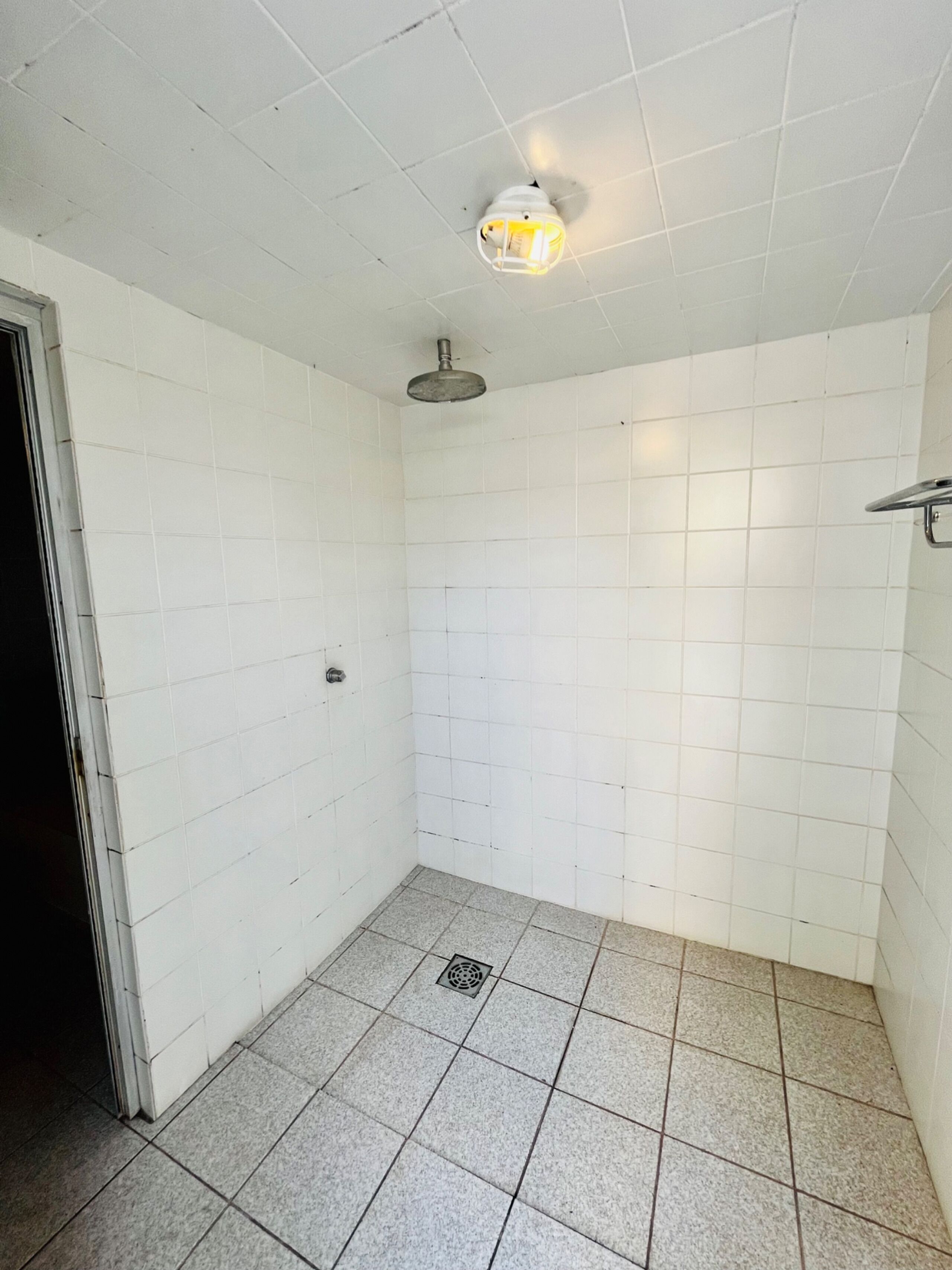 A small, tiled bathroom with a shower, a toilet, and a sink.