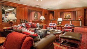 A spacious lobby with leather sofas, patterned armchairs, and a chandelier.