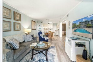 A living room with a sofa, coffee table, and a TV on a stand. - Enjoy a Stay at Sea Cabin 210 (North Myrtle Beach)