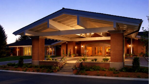 A hotel with a covered entrance, brick facade, and a well-lit driveway. - 2 King | Little America | Oversized Comfort, 80 Acres, Golf, Seasonal Pool (Cheyenne)