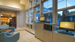 A modern office space with two monitors, a keyboard, and a glass desk.