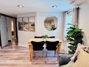 A dining area with a wooden table, black chairs, a mirror, and a potted plant. - Stunning, spotless two-bed basement suite in newly renovated duplex (Idaho Falls)