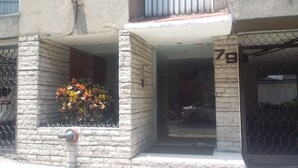 A building entrance with a stone facade, a metal gate, and a number '79' on the wall. - executive room Leo (Mexico City)