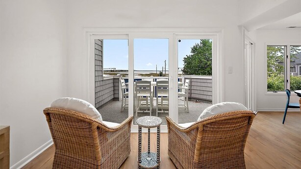 A room with wicker chairs, a small table, and a view of the outside. - Three Bedroom Bay View Townhome in Fenwick Island (Fenwick Island)