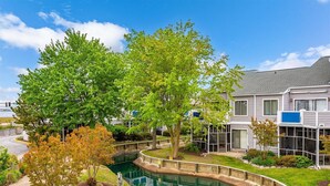 A residential area with a swimming pool, a house with a covered porch, and a clear sky. - Three Bedroom Bay View Townhome in Fenwick Island (Fenwick Island)