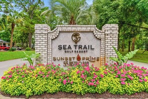 A sign for Sea Trail Golf Resort with a brick wall and a logo. - Unique Treehouse Getaway in Sea Trail - Sunset Beach (Sunset Beach)