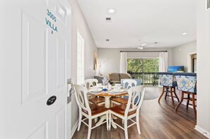 A dining area with a table set for four, a sofa, and a TV in the background. - Unique Treehouse Getaway in Sea Trail - Sunset Beach (Sunset Beach)