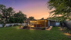 A backyard with a covered patio, a fire pit, and a small garden area. - Big Tree (Daytona Beach)