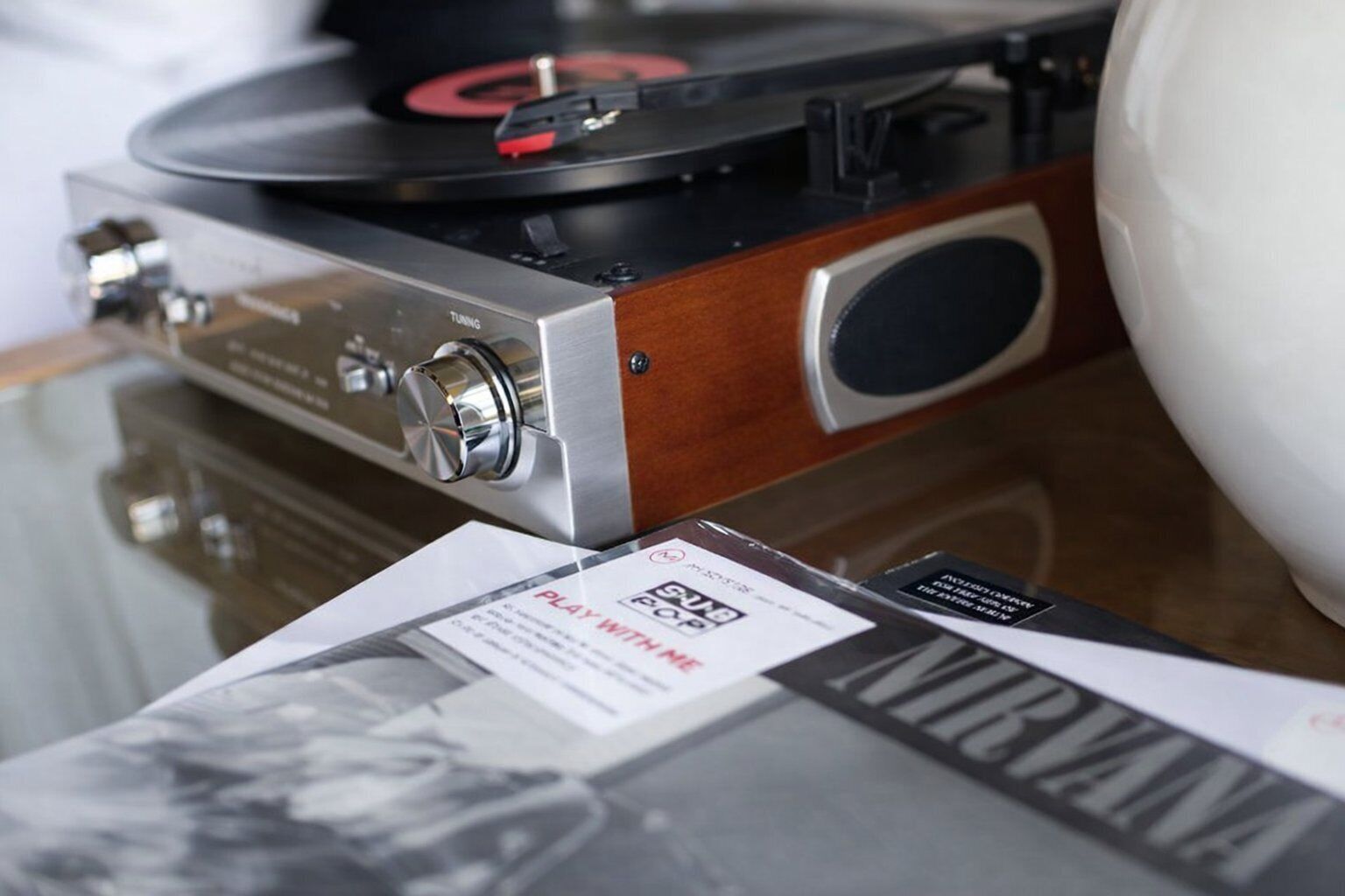 Tocadiscos con detalles de madera, un mando de ajuste y un disco encima.