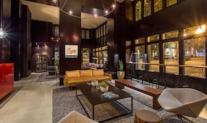 A modern lobby with a leather sofa, a coffee table, and a red accent wall. - Hotel Max | Pop King | Vinyl Moments, Photo Art, Pike Place + MoPOP Nearby (Seattle)