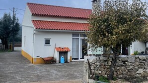 A two-story building with a red-tiled roof, a small porch, and a stone wall. - Ti Zaquiel Farm (Porto de Mós)