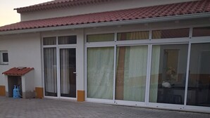 A building with a tiled roof, large windows with curtains, and a brick-paved ground. - Ti Zaquiel Farm (Porto de Mós)