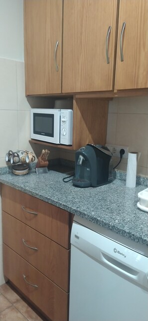 A kitchen with wooden cabinets, a microwave, a coffee maker, and a dishwasher.