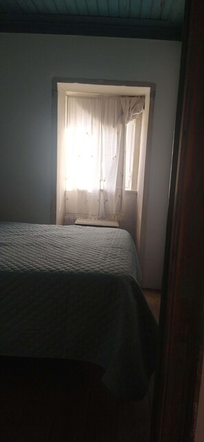 Une chambre à coucher avec un lit, une fenêtre avec des rideaux et un plafond en bois.