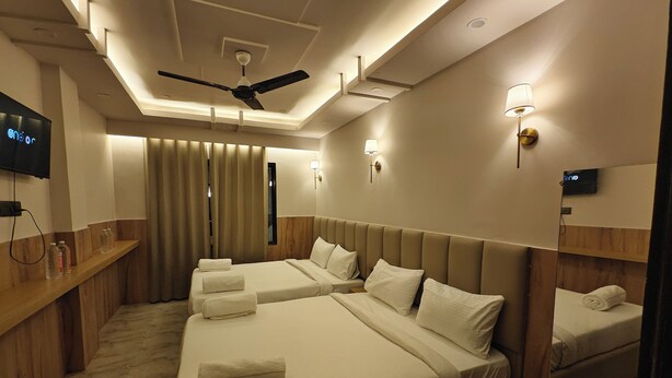 Habitación de hotel con dos camas, ventilador de techo, televisor y espejo.