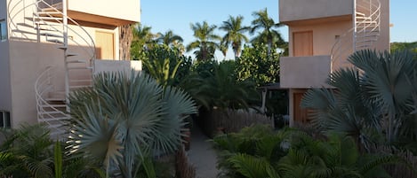 A modern building with spiral staircases, surrounded by lush tropical plants and palm trees.