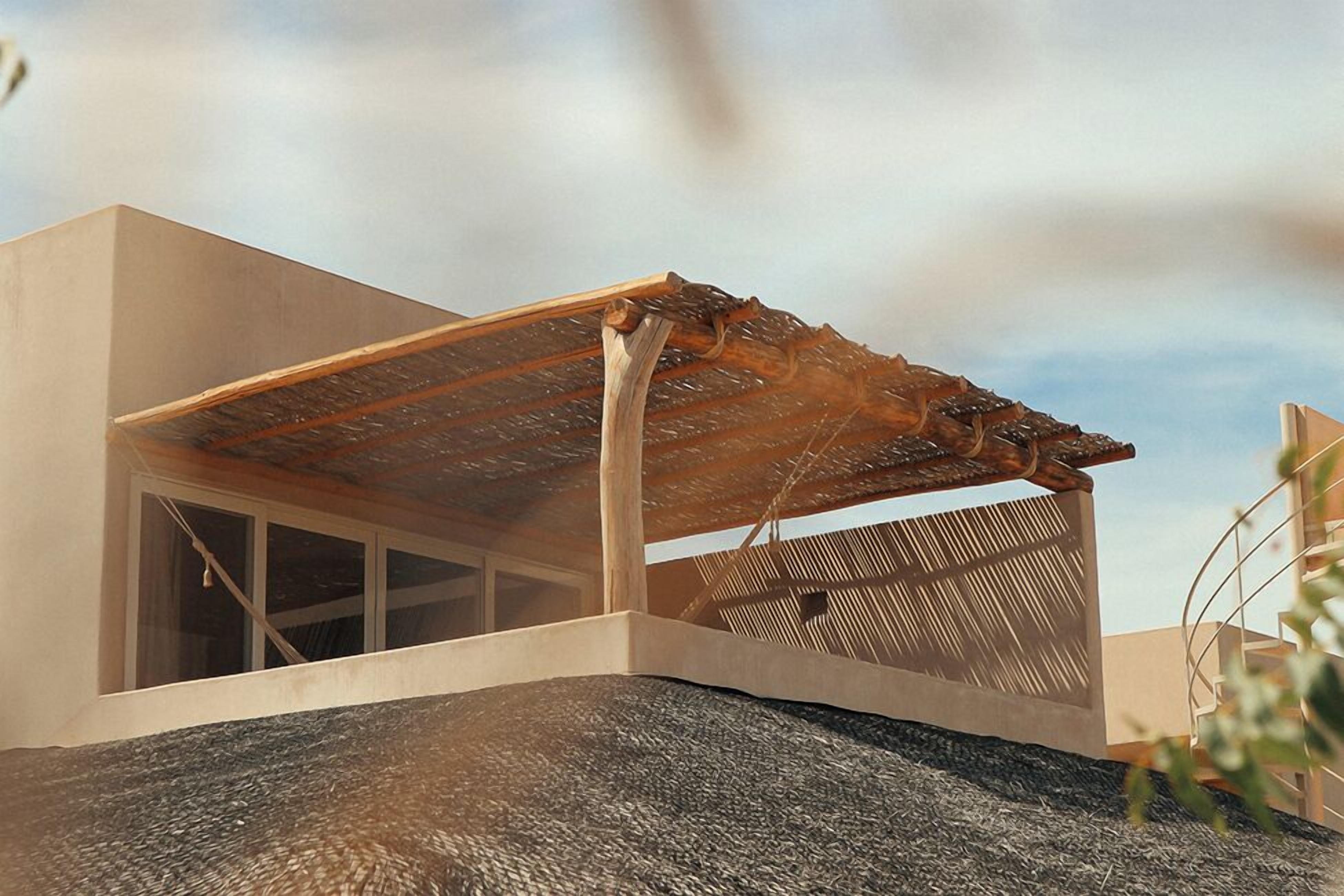 Een modern gebouw met een plat dak, een groot raam en een houten constructie op het dak.