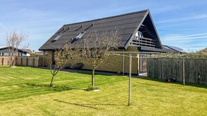 Une maison avec un toit en pente, une cour arrière clôturée et un ciel dégagé.