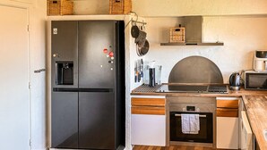 Une cuisine de taille réduite, dotée d’un réfrigérateur noir, d’un four Bosch et d’un four à micro-ondes.