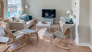 Una sala de estar con sofá, sillas, una mesa de centro, televisor y chimenea.