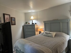 Ein Schlafzimmer mit einem Bett, einem Schminktisch, einer Lampe und einem Schild am Kopfteil.