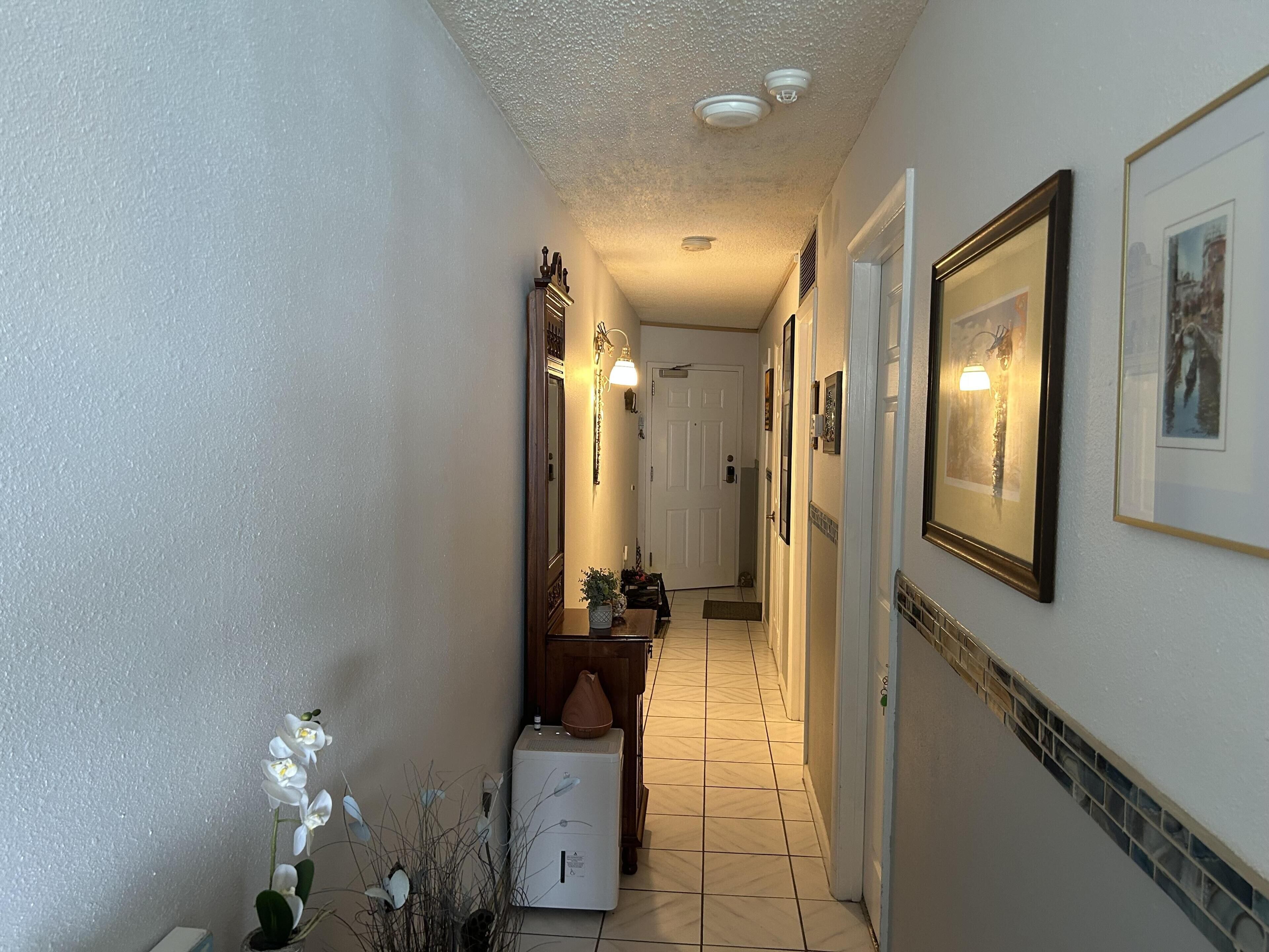 A hallway with a white refrigerator, a bench, and a door at the end.