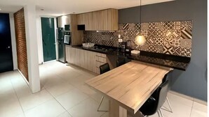 Uma cozinha moderna com mesa de jantar de madeira, cadeiras pretas e painel decorativo.