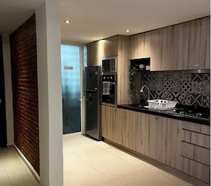 Eine moderne Küche mit Holzschränken, einem Edelstahlkühlschrank und einer schwarzen Arbeitsplatte.