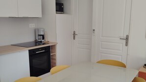 A compact kitchen with a coffee machine, a dishwasher, and a white refrigerator. There is a dining table with yellow chairs and a white tablecloth. - Mobile home with 4 bedrooms for 8 people (Sainte-Marie-la-Mer)