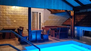 Una piscina interior con mobiliario de madera y una pared de piedra.