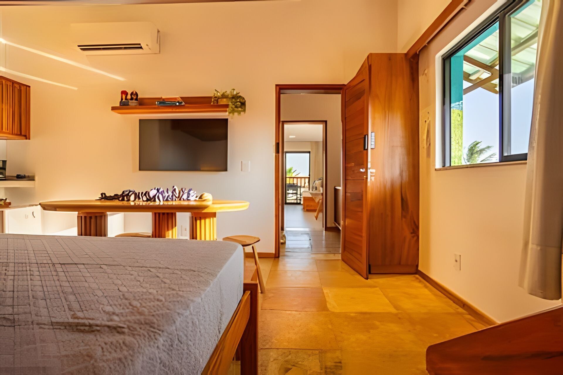 Ein modernes Hotelzimmer mit Bett, Schreibtisch, Fernseher und Blick ins Freie.