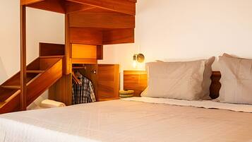 Ein Schlafzimmer mit einem Bett, einem Nachttisch, einer Lampe und einer Holztreppe.