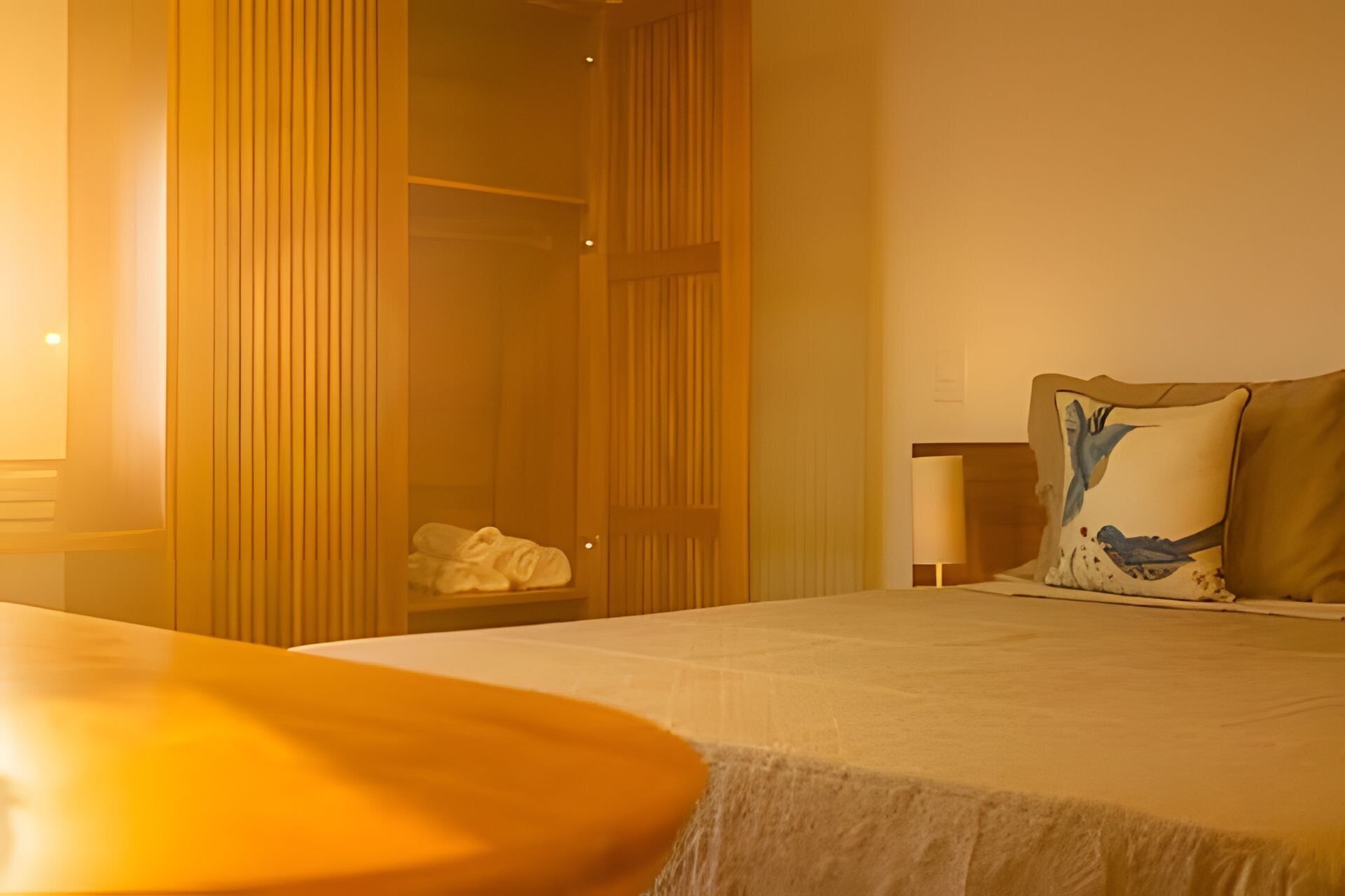 A hotel room with a bed, a bedside table, a lamp, and a wardrobe.