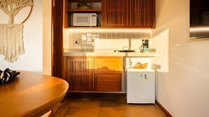 A compact kitchen with wooden cabinets, a microwave, a coffee maker, and a refrigerator. - ARARA HOUSE  (Jijoca de Jericoacoara)