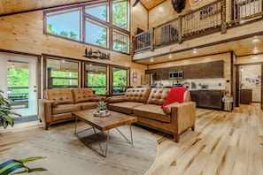 Un amplio salón con un sofá modular grande, una mesa de centro y una cocina al fondo.
