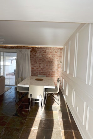 A dining area with a brick wall, a white table, and chairs. - Private Pool + Detached Bunkhouse | Sleeps 10 (Scottsdale)