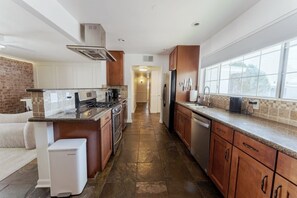 A modern kitchen with a central island, stainless steel appliances, and a view to the outside. - Private Pool + Detached Bunkhouse | Sleeps 10 (Scottsdale)