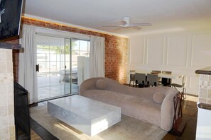 A living room with a sofa, a coffee table, a fireplace, and a dining area with chairs and a table. - Private Pool + Detached Bunkhouse | Sleeps 10 (Scottsdale)