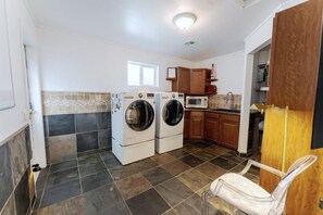 A laundry area with two washing machines, a microwave, and wooden cabinets. - Private Pool + Detached Bunkhouse | Sleeps 10 (Scottsdale)
