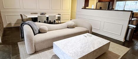 Una sala moderna con un sofá seccional, una mesa de centro y un comedor con una mesa y sillas.