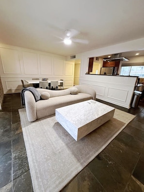 A modern living room with a sectional sofa, a coffee table, and a dining area with a table and chairs. - Private Pool + Detached Bunkhouse | Sleeps 10 (Scottsdale)