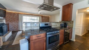 Una cocina con estufa a gas, horno y pared de ladrillo.