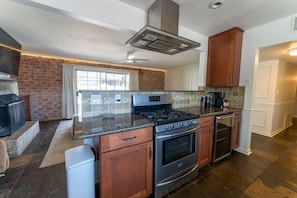 A kitchen with a gas stove, oven, and a brick wall. - Walk to Old Town Pool + Bunkhouse | Sleeps 8 (Scottsdale)