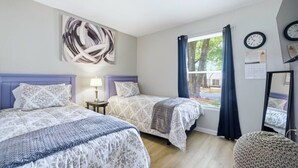 A bedroom with two beds, a window with curtains, a wall clock, and a calendar. - Ice Bath, Fire Pit & Outdoor Bar · 3BR House · Uptown Charlotte (Charlotte)
