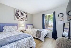 A bedroom with two beds, a window with curtains, a wall clock, and a calendar. - Ice Bath, Fire Pit & Outdoor Bar · 3BR House · Uptown Charlotte (Charlotte)