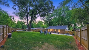 A backyard with a wooden fence, a trampoline, and a house with a patio. - Ice Bath, Fire Pit & Outdoor Bar · 3BR House · Uptown Charlotte (Charlotte)